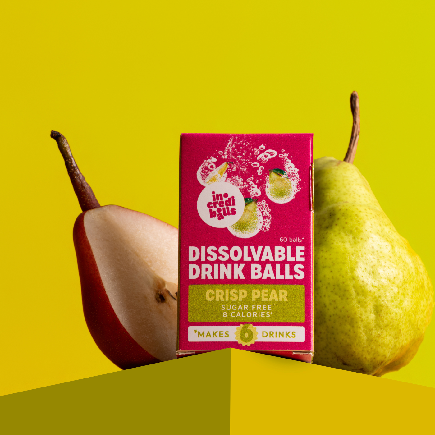 Incrediballs Crisp Pear dissolvable drink balls pack with fresh pears on a yellow background